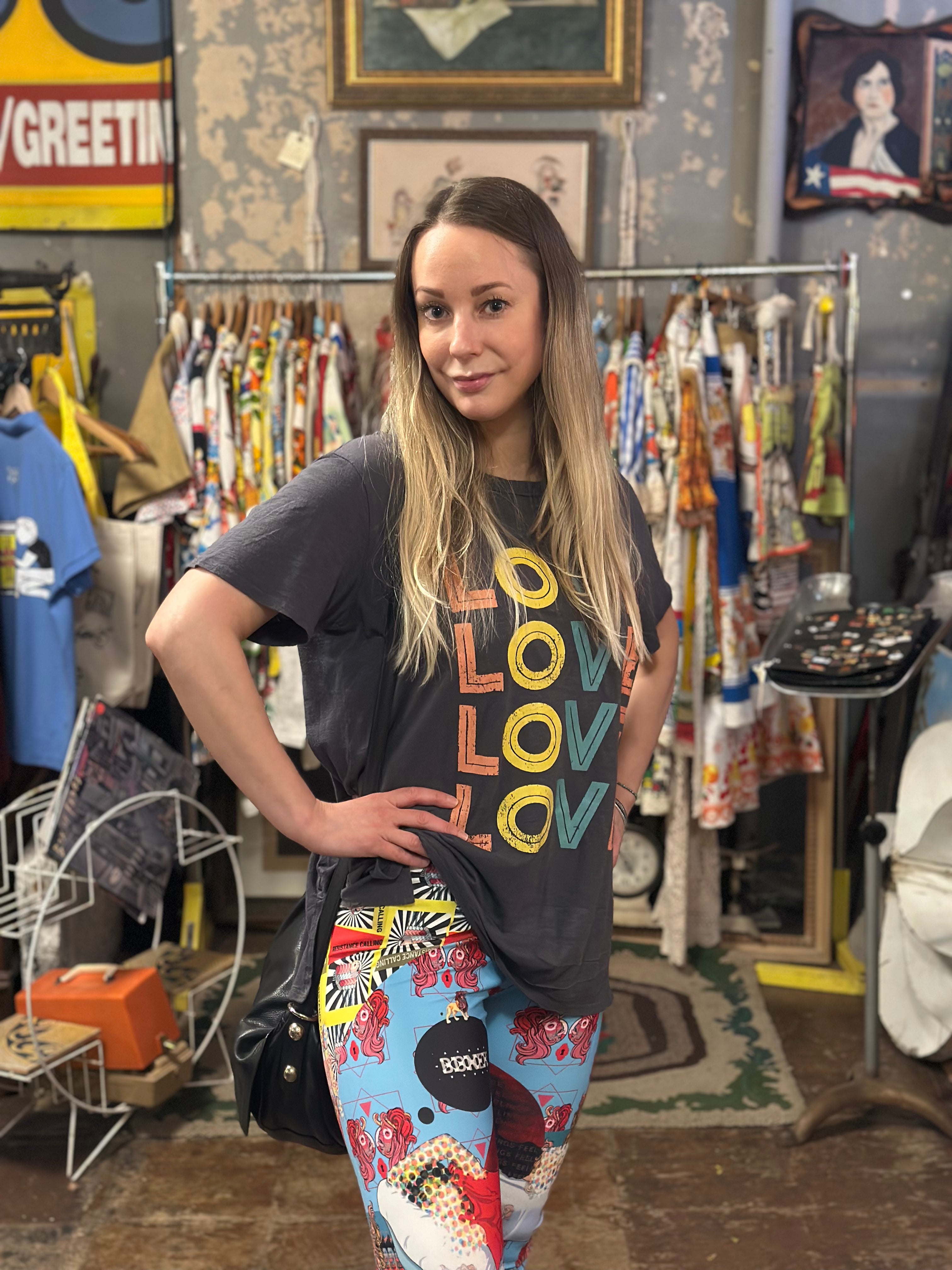 Woman wearing a graphic t-shirt and colorful pants in a vintage store setting