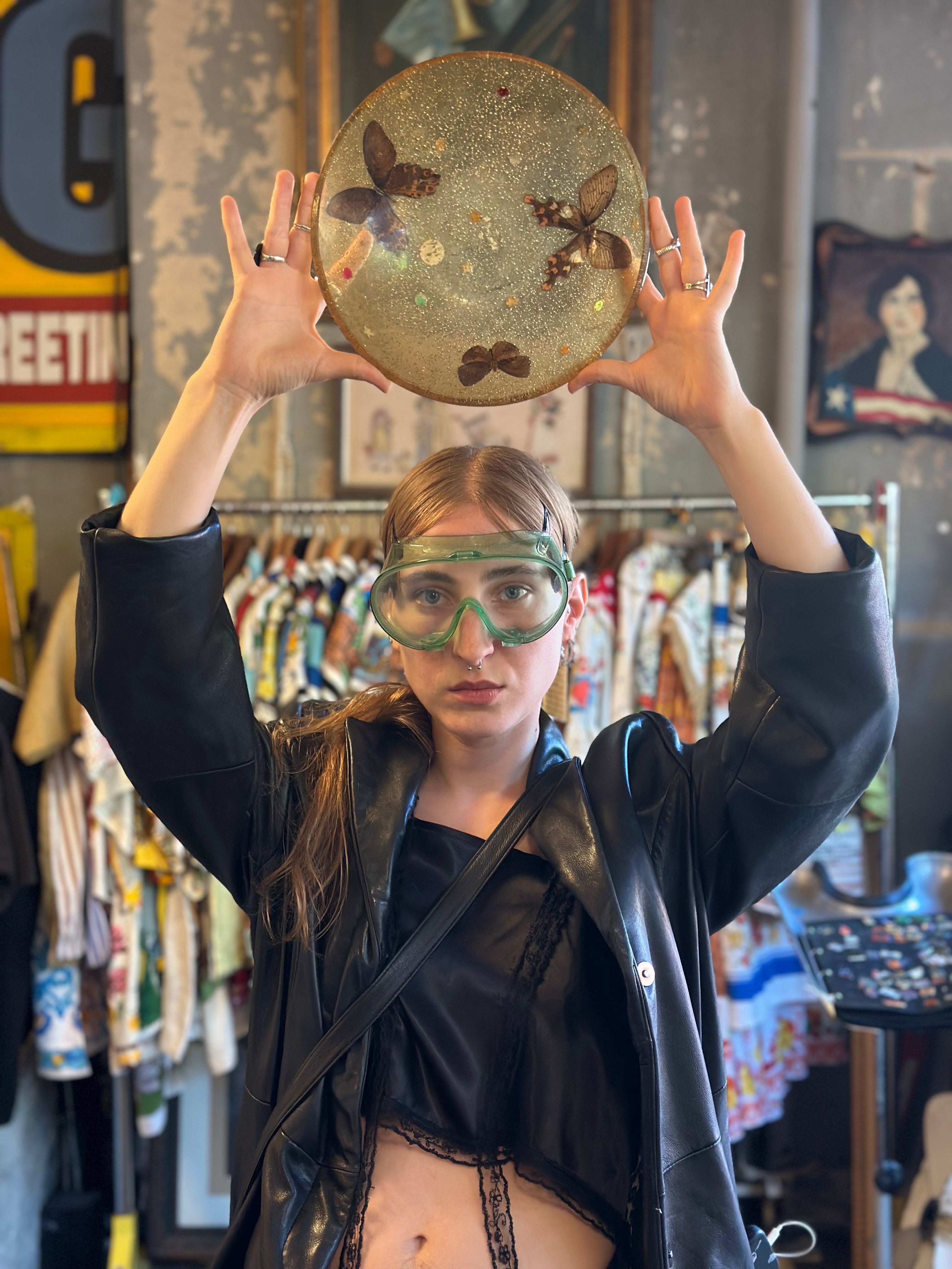 Person holding a round object with butterfly designs above their head in a store setting.