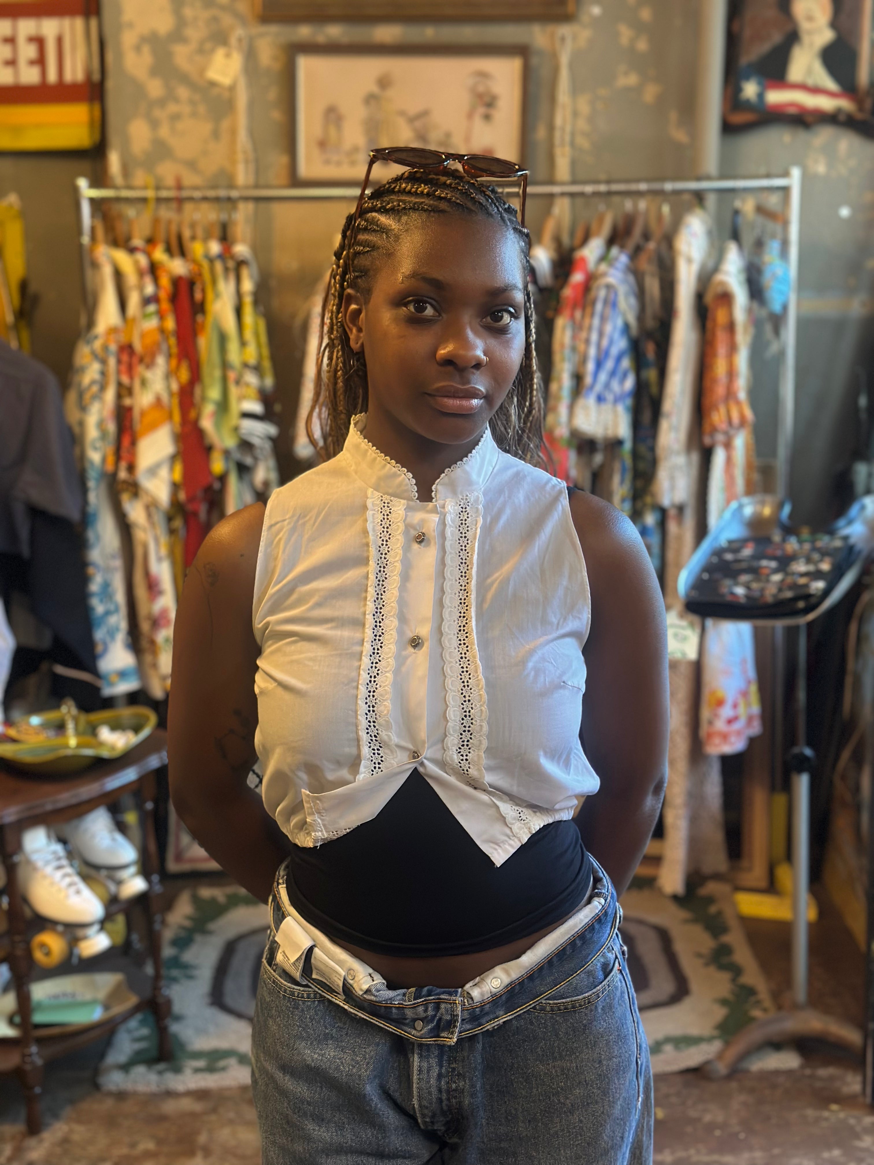 Woman standing in a vintage clothing store with racks of clothes in the background