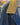 Close-up of a blue denim jacket with a yellow collar and a blurred background