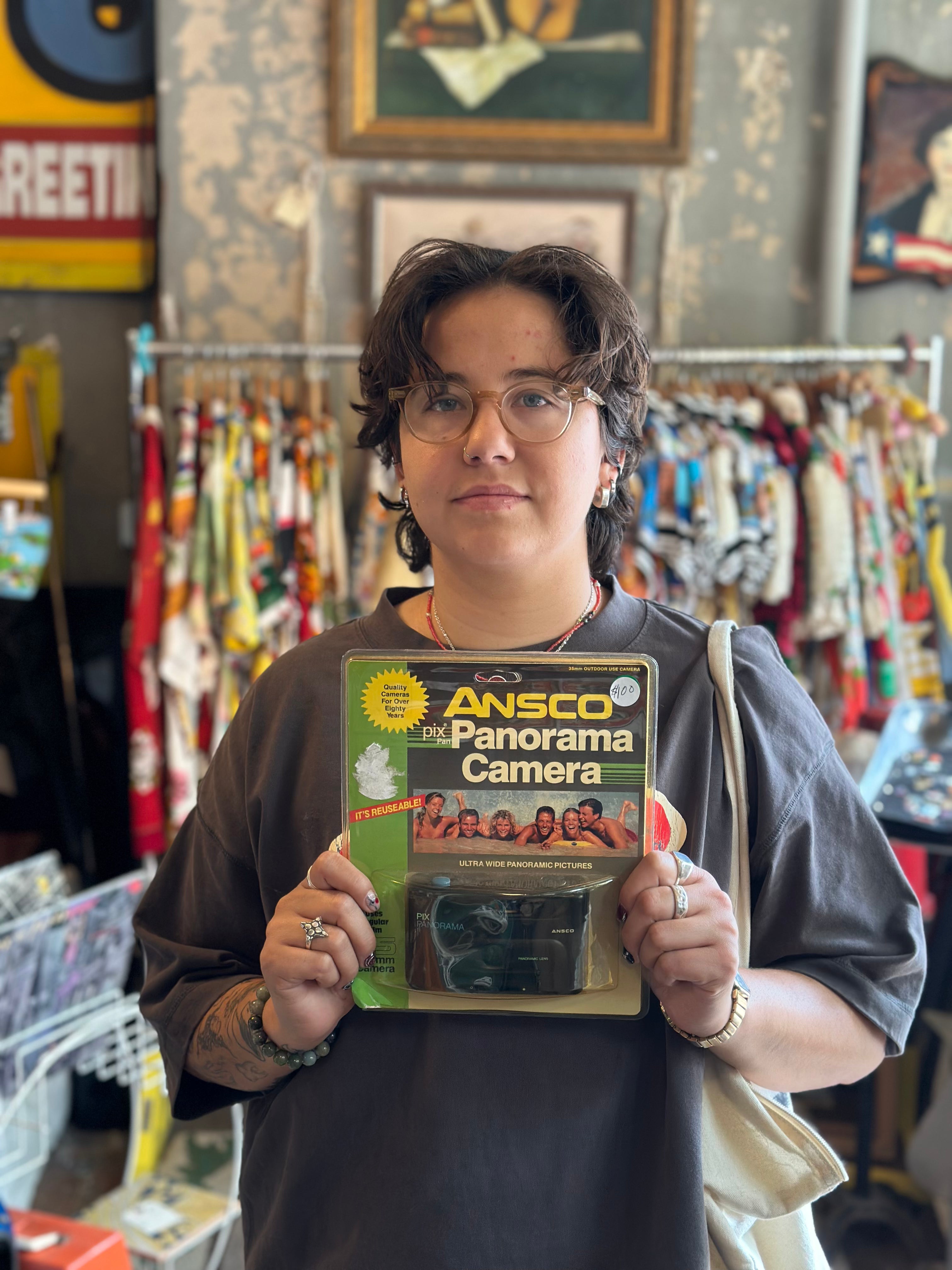 Person holding an Ansco Panorama Camera box in a vintage store setting