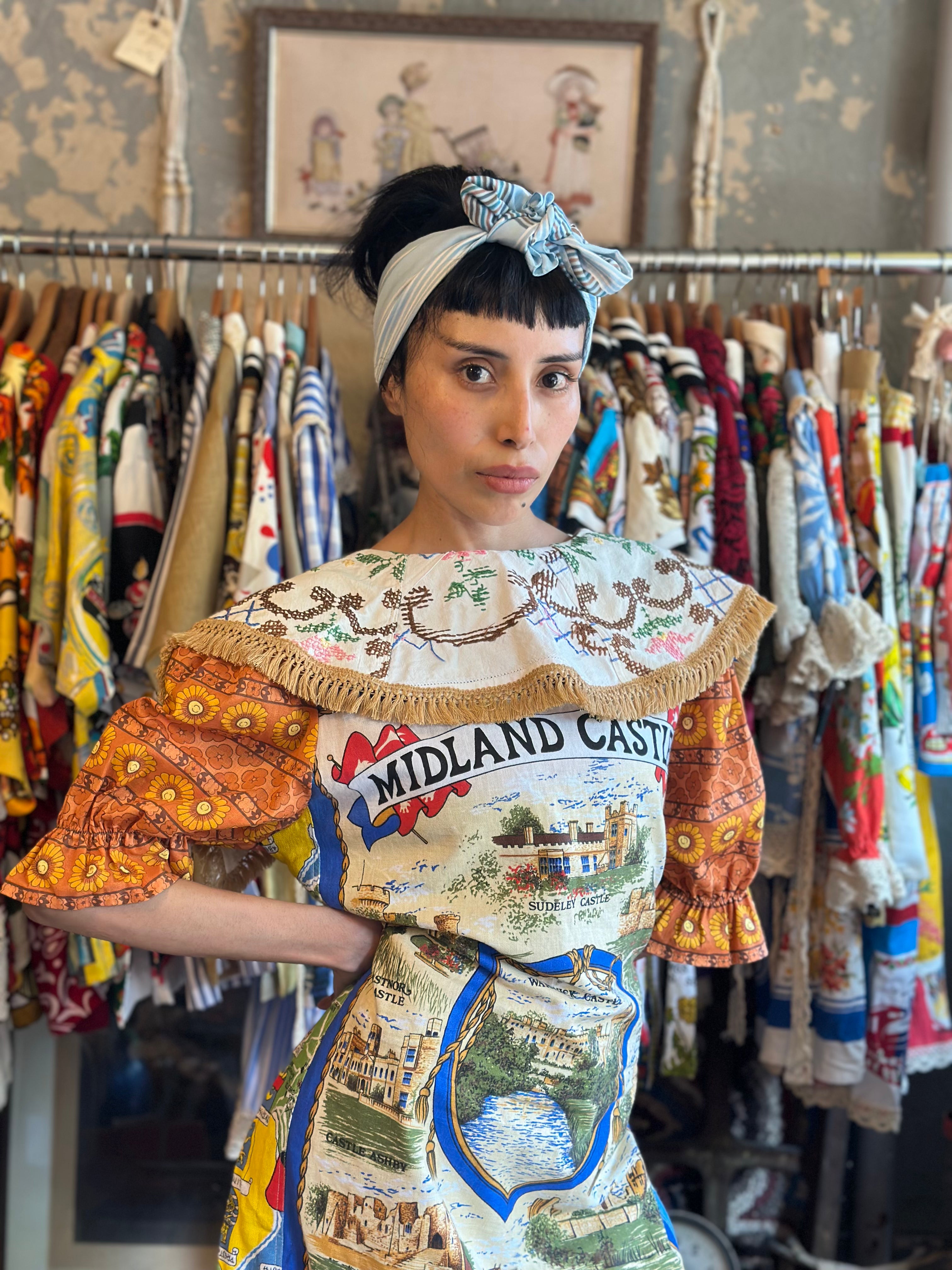 Person wearing a colorful dress with 'Midland Castle' text in a vintage clothing store.